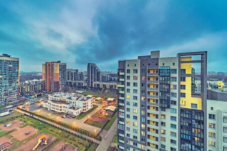New modern residential buildings with lit windows in evening suburbia districtの写真素材