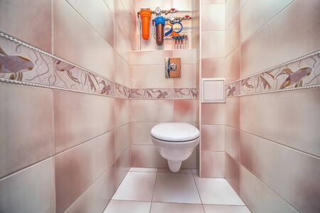Toilet bowl in the toilet room. Restroom with beige tile decoration and flooringの写真素材
