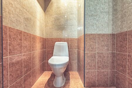 Toilet bowl in the toilet room. Restroom with beige tile decoration and flooringの写真素材