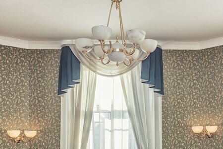 Huge chandelier close up with electric bulbs on fancy ceilingの写真素材
