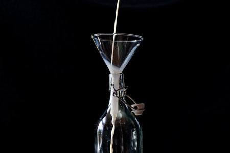 Retro closeup of neck bottle on black background. Milk splash background. Organic farming concept....