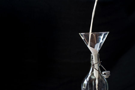Retro closeup of neck bottle on black background. Milk splash background. Organic farming concept....