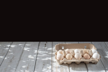 cardboard box of chicken eggs. farm products. white table black background.