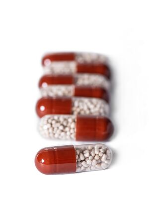 a handful of two-tone tablets on a white background, capsules with granules inside, vitamins, care healthの写真素材