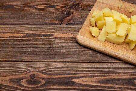 Fresh organic products. Wooden plank. Raw Potatoes Diced Flat lay.の写真素材