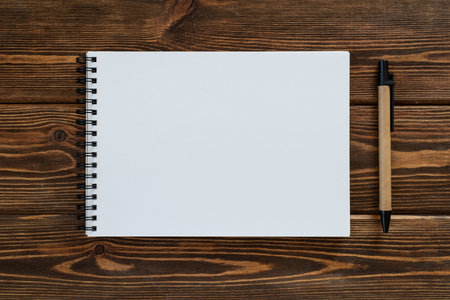 A wooden table. Empty notebook and pen - top view. High resolution photo.