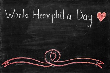 April 17 World Hemophilia Day. drawing on the blackboard, red heart and ribbon. empty space for inscriptionの写真素材