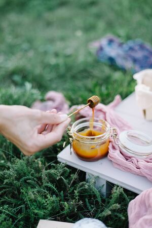 female hands hold a spoon in caramel. garden picnic birthday celebration.の写真素材