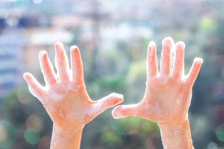 Childrens hands in soap suds on the background of natureの写真素材