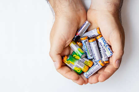 Mens hands hold batteries and used batteries on white background. Isolated.The recycling of batteries. collection and recycling of dangerous wasteのeditorial素材