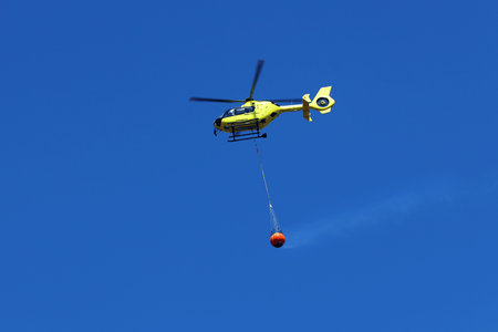 Firefighting helicopter carry water bucket to extinguish the fire or forest fire.