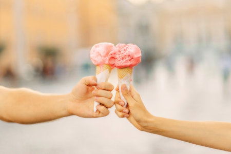 Mens and womens hands hold bright ice cream cone. Hands holding ice cream cone. Summertime. Tourist...
