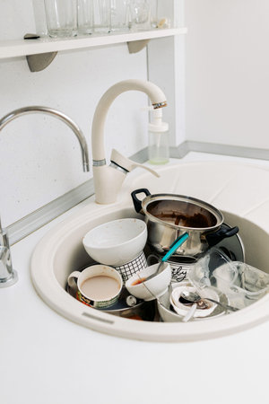 Dirty dishes in kitchen after lunch in the kitchen sink. Mess in the kitchen. Vertical photo. Home routine.の写真素材