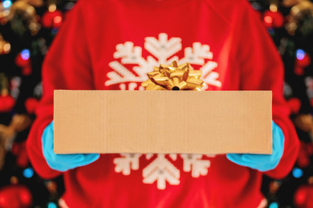 Delivery man holding cardboard boxes, gift in medical rubber gloves on the background of a Christmas...