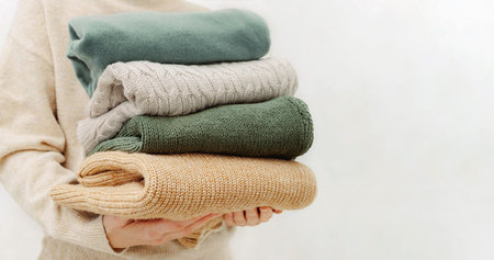 Womans hand holding a stack of clothes. Clothes Donation, Renewable Concept.Preparing Garment at...