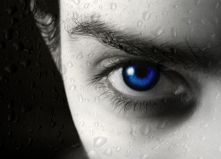 Photo of half of face of the beautiful young blue-eyed girl and drop of a rain on glassの写真素材