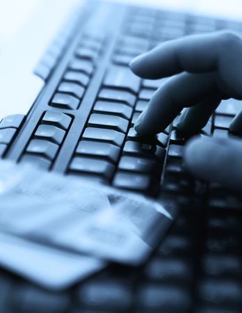 Tinted blue photo with computer keyboard, credit cards and handsの写真素材