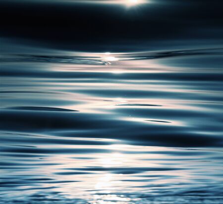 Sunshine sparkling sea waves at sunset beachの写真素材
