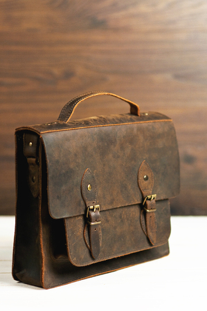 Bag briefcase for businessman men, leather brown bag on a wooden background. Men's fashion, accessory, business background. Selective focus.の写真素材