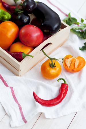 Fresh vegetables, tomatoes, peppers, aubergines, chilli pepper in a wooden box in the open air. Vegetable background.の写真素材