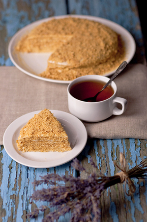 A cup of tea and a honeycomb with lavender on a wooden blue background. Homemade cake baking cup of tea lavender wooden background. Dessert, sweets, vintage backgroundの写真素材