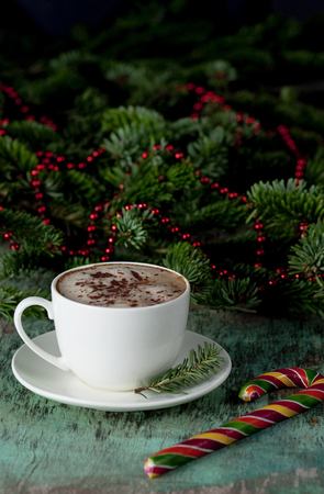 A cup of coffee on a wooden background. Coffee cappuccino with Christmas fir branches and ornaments on old wooden background. Festive decoration, postcardの写真素材