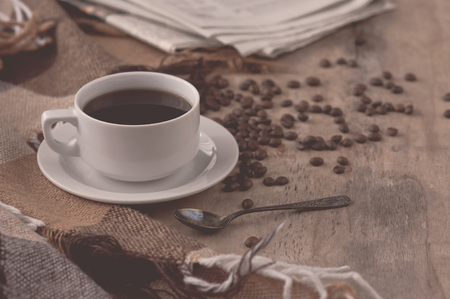 A cup of coffee Black coffee hot drink Grains Newspapers Wooden background Checkered Plaid Heart Fall Autumn winter drink Tinted effectの写真素材