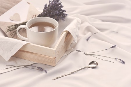 A tray with a cup of hot tea and lavender love letter in bed. Herbal tea Hot drink Mood Love Message Breakfast in bed Morning Lifestyleの写真素材
