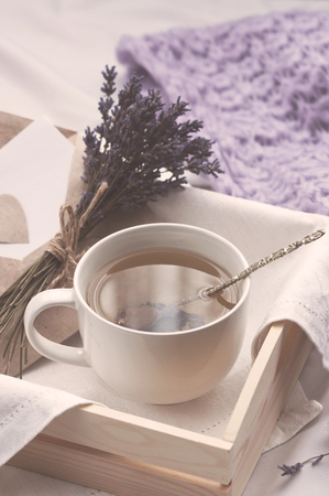 A tray with a cup of hot tea and lavender love letter in bed. Herbal tea Hot drink Mood Love Message Breakfast in bed Morning Lifestyleの写真素材