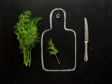 Concept of healthy eating, process of cooking, a healthy lifestyle. Fresh dill on a hand-drawn cutting board, knife on a black background top view. Food backgroundの写真素材