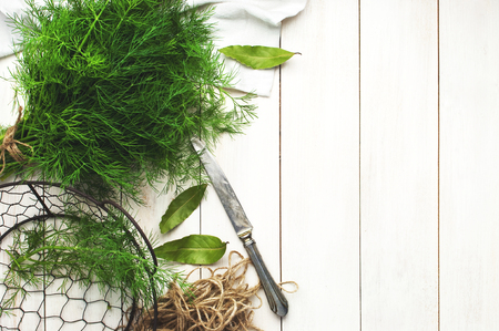 Fresh dill on a cutting board with a knife and bunches of dill on a white wooden table top view. Fresh greens, seasoning, the process of cooking dishes, a healthy lifestyle. Food backgroundの写真素材