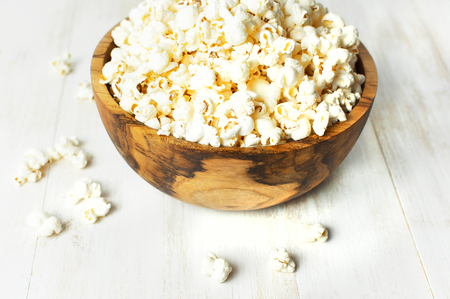 Brown wooden bowl with delicious traditional popcorn on a light wooden background. Top view of a light meal background. Corn Dishesの写真素材