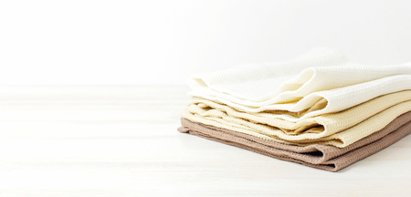 Multicolored clean towels on a light wooden background with copy space. Texture of cotton, waffle towel, textiles. Towels for kitchen or Spa concept. Isolated objectの写真素材