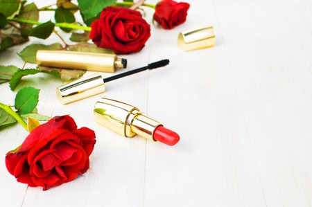 Various cosmetic products for make-up with red roses on a white wooden background with copy space. Makeup Accessories Red lipstick Black mascara Selective focus. Women's thingsの写真素材