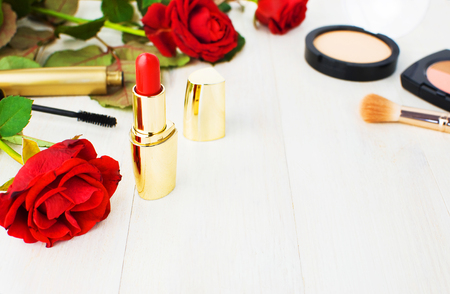 Various cosmetic products for make-up with red roses on a white wooden background with copy space. Makeup Accessories Red lipstick Selective focus. Women's thingsの写真素材