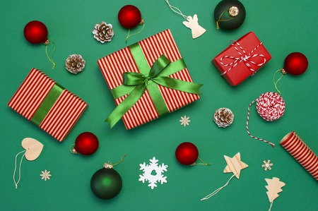 Gift boxes, Christmas balls, toys, fir cones, ribbon on green background. Festive, congratulation, New Year Christmas presents Xmas holiday 2019 greeting card. Flat lay, top viewの写真素材