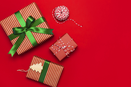 Gift boxes with green ribbon on red background top view flat lay. Holiday concept, new year or Christmas gift box, presents Xmas holiday. Congratulations background space for text.の写真素材