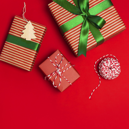 Gift boxes with green ribbon on red background top view flat lay. Holiday concept, new year or Christmas gift box, presents Xmas holiday. Congratulations background space for text.の写真素材
