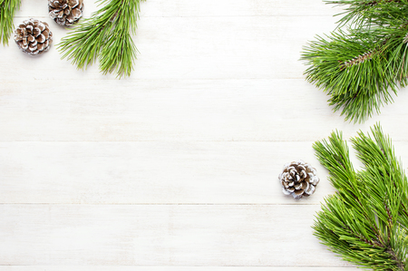 Christmas background, green pine branches, cones decorated with snow on white wooden table. Creative composition with border and copy space design top view. New Year's, holiday, decorationの写真素材