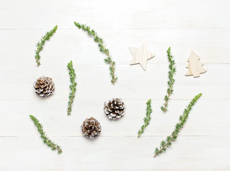 Fir branches, cones, wooden toys on white wooden table Flat lay top view copy space square.の写真素材