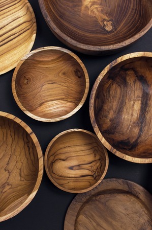 Wooden utensils for the kitchen, bowls and plates on a black background. The concept of natural dishes, a healthy lifestyle. Texture of wood.の写真素材