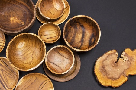 Wooden utensils for the kitchen, bowls and plates on a black background. The concept of natural dishes, a healthy lifestyle. Texture of woodの写真素材
