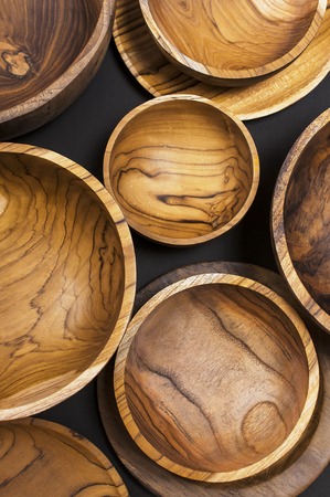 Wooden utensils for the kitchen, bowls and plates on a black background. The concept of natural dishes, a healthy lifestyle. Texture of woodの写真素材