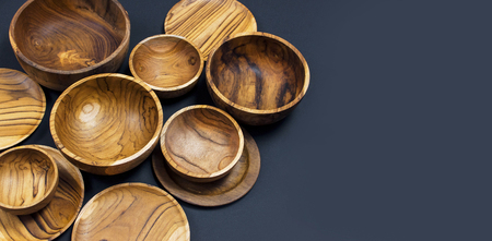 Wooden utensils for the kitchen, bowls and plates on a black background. The concept of natural dishes, a healthy lifestyle. Texture of woodの写真素材