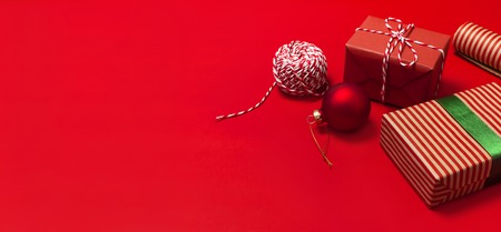 Gift boxes, Christmas balls, toys, fir cones, ribbon on red background. Festive, congratulation, New Year Christmas presents Xmas holiday 2019 greeting card. Flat lay top view, copy space.の写真素材
