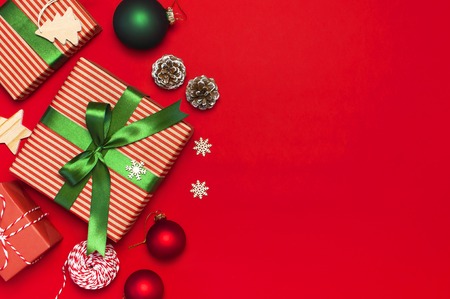 Gift boxes, Christmas balls, toys, fir cones, ribbon on red background. Festive, congratulation, New Year Christmas presents Xmas holiday 2019 greeting card. Flat lay top view, copy space.の写真素材