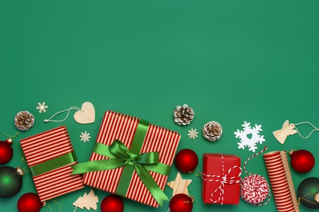 Gift boxes, Christmas balls, toys, fir cones, ribbon on green background. Festive, congratulation, New Year Christmas presents Xmas holiday 2019 greeting card. Flat lay top view, copy space.の写真素材