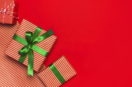 Gift boxes with green ribbon on red background top view flat lay. Holiday concept, new year or Christmas gift box, presents Xmas holiday. Congratulations background with space for text.の写真素材