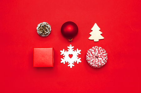 Christmas composition. New Year's wooden toys, fir cones, red ball, snowflake, gift twine on red background Flat lay top view copy space. Christmas winter decoration Nature New Year conceptの写真素材