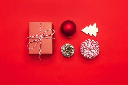 Christmas composition. New Year's wooden toys, fir cones, red ball, snowflake, gift twine on red background Flat lay top view copy space. Christmas winter decoration Nature New Year conceptの写真素材